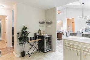 Eine moderne Küche mit einer Kaffeestation, einem Essbereich mit gestreiften Stühlen und einem großen Schrank.