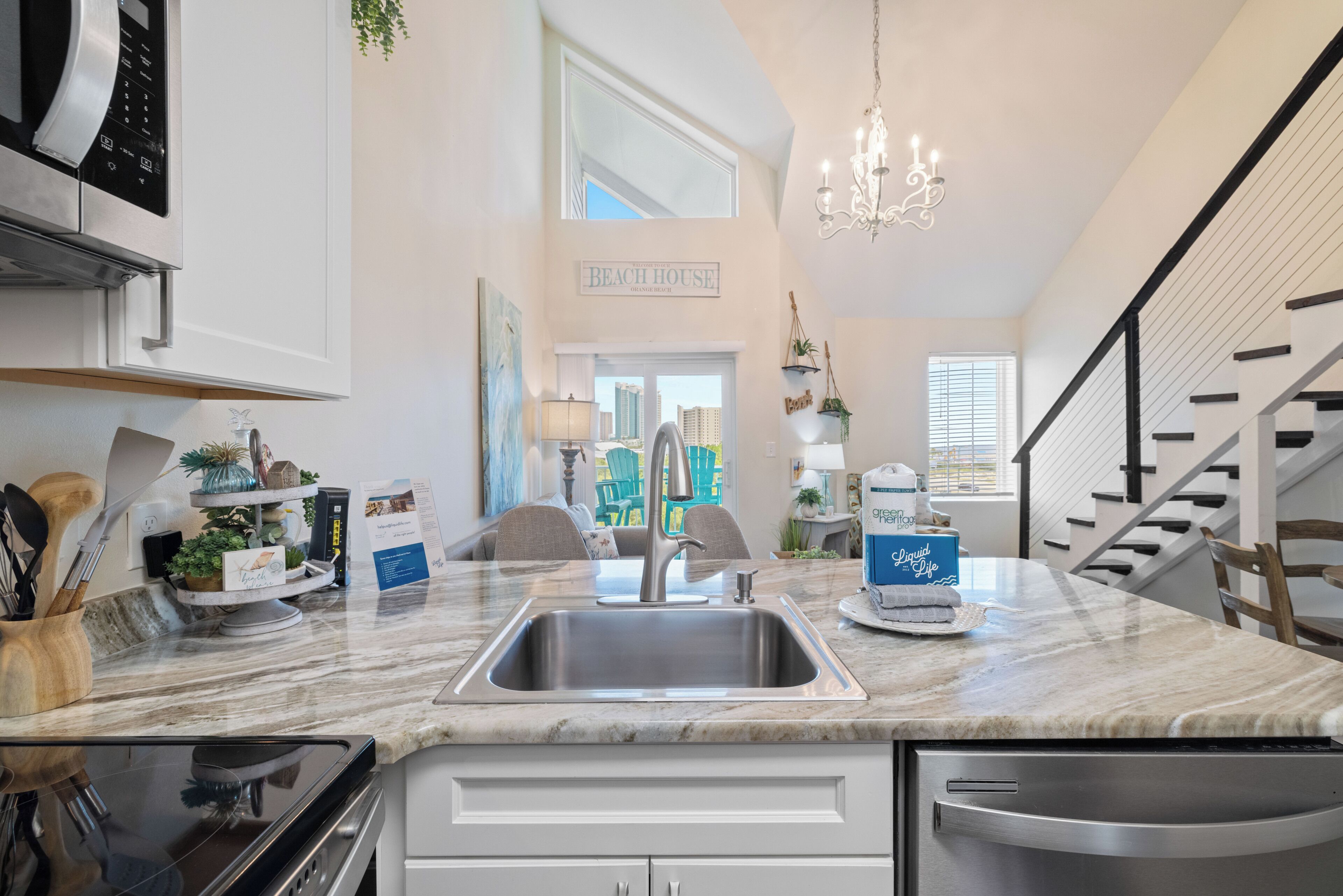 A kitchen with a large island, stainless steel appliances, and a view to the outside.