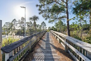 A wooden boardwalk with railings, surrounded by trees and vegetation. - Grand Caribbean 425 by Liquid Life (Orange Beach)