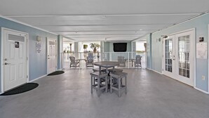 A hallway with a round table and four stools, doors with signs, and a view of the outside. - Grand Caribbean 425 by Liquid Life (Orange Beach)