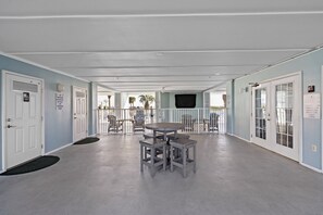 A hallway with a round table and four stools, doors with signs, and a view of the outside. - Grand Caribbean 425 by Liquid Life (Orange Beach)