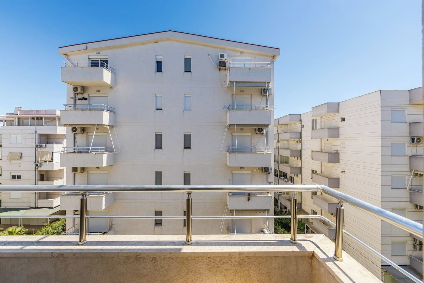 Un edificio residenziale a più piani con balconi, un tetto piano e cielo sereno.