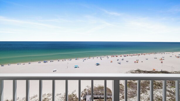Ein Strand mit einer Holzterrasse, blauem Himmel und ruhiger See.