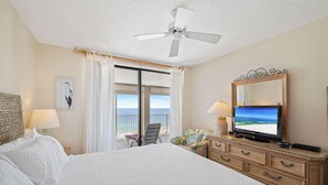 Ein Hotelzimmer mit einem großen Bett, einem Fernseher, einem Schminktisch und einem Balkon mit Blick.