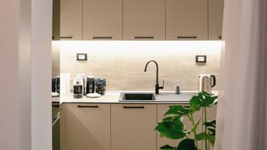 Een moderne keuken met beige kastjes, een zwarte kraan en een potplant.