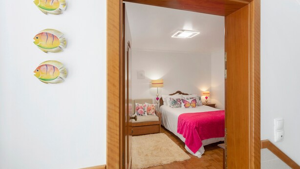 Ein Schlafzimmer mit Bett, Nachttisch, Lampe und einer Tür zu einem anderen Raum.