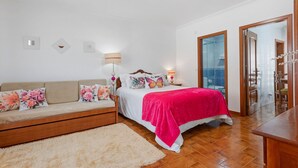 Ein Schlafzimmer mit Bett, Sofa, Nachttisch und Spiegel.