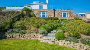 A stone house with a stone staircase, a stone wall, and a grassy area. - Luxury Coastal Cottage With Harbour Views (St Austell)
