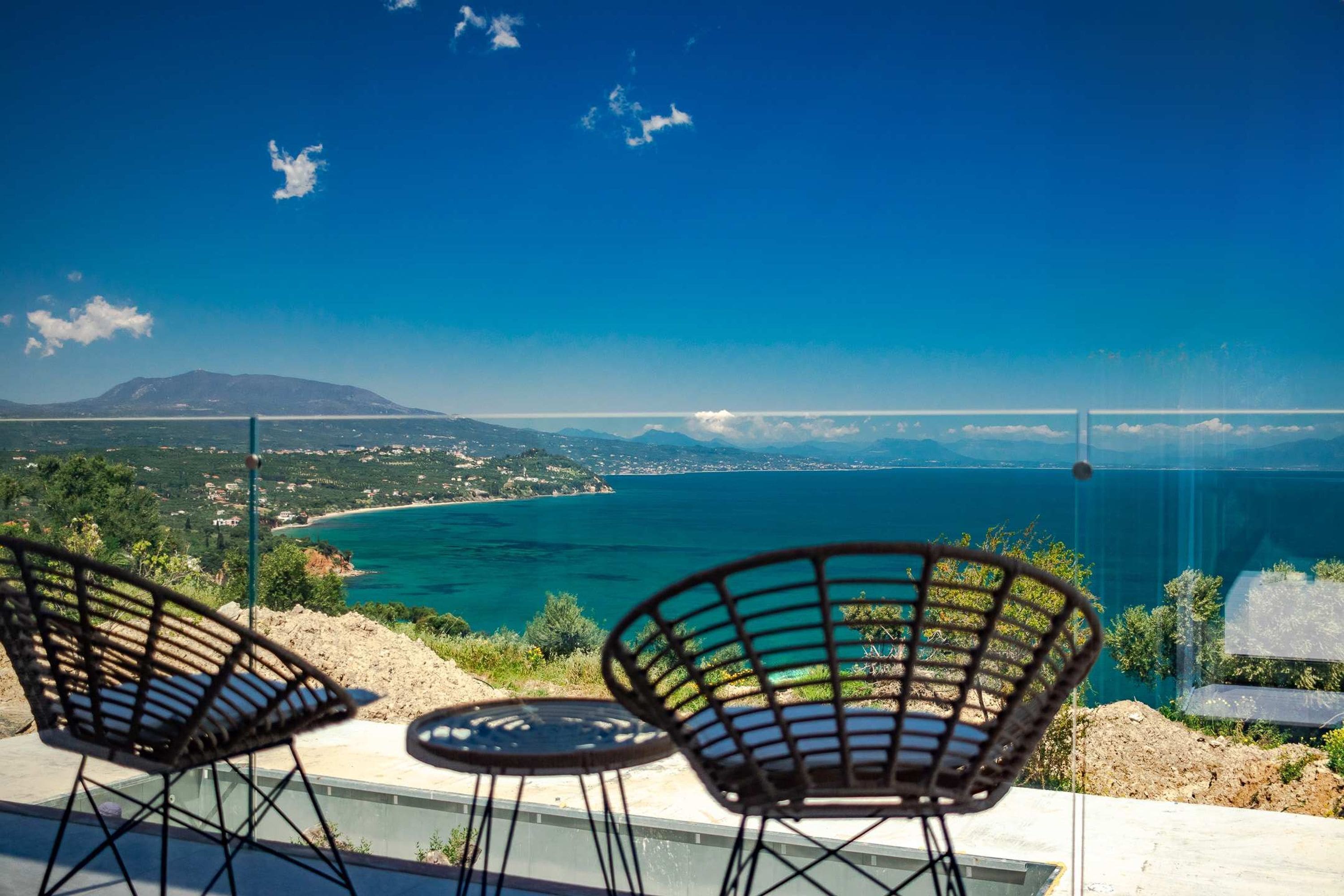 A terrace with two chairs overlooking a coastal view.