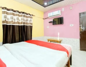 A bedroom with a bed, a bedside table, a mirror, an air conditioning unit, and a door. - Kiran Himachal Pradesh (Jhanduta)