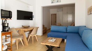 Ett modernt vardagsrum med en soffa, TV, soffbord och en matplats med stolar och ett bord.