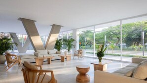 Eine moderne Lobby mit einer V-förmigen Decke, bequemen Sitzgelegenheiten und großen Fenstern mit Blick auf Grünflächen.