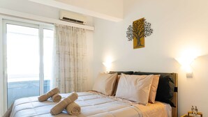 A neatly made bed with rolled towels, a nightstand with a lamp, and a wall-mounted artwork. - Sinani Beachfront Gems Rhodes Jacuzzi Retreat (Rhodes)