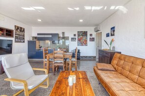 Un salon moderne avec une table basse en bois, un canapé en cuir et un coin repas comprenant des chaises et une table en bois.