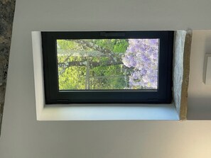 A skylight window with a view of trees and purple flowers. - Dwelling Forest on the Blue (Ameglia)