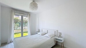 Et soveværelse med seng, natborde, en hængende lampe og en skydedør til en balkon.