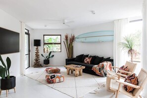 Ein Wohnzimmer mit einer schwarzen Couch, einem Holztisch und Korbstühlen.