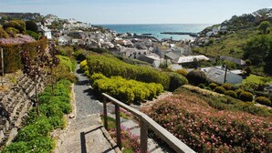 A coastal village with stone pathways, lush greenery, and a view of the sea. - Breath-taking Estate With Pool Tennis Court Sea Views (St Austell)