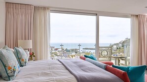 A hotel room with a large bed, a view of the sea, and a balcony with a table and chairs. - Breath-taking Estate With Pool Tennis Court Sea Views (St Austell)