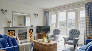 A living room with a fireplace, television, and seating area with a view. - Breath-taking Estate With Pool Tennis Court Sea Views (St Austell)