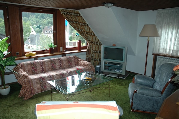 Un salon comprenant un canapé, une table basse en verre, un téléviseur, une lampe et un fauteuil.