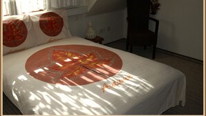 Ein Schlafzimmer mit einem Bett, Kissen, einem Sessel, einem Nachttisch und einer Lampe.