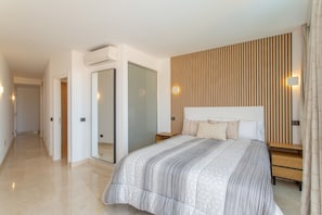 Une chambre à coucher moderne avec un grand lit, un mur recouvert de panneaux en bois, un miroir et une table de chevet avec une lampe.
