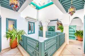 A courtyard with a central seating area, green railings, and hanging lanterns. - New, luxury, 4BR 4,5 bath Riad UNIVERSE , enchanting rooftop with pool , new AC (MARRAKECH)
