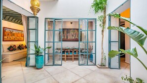 Une pièce comprenant une table à manger, des chaises, une plante en pot et un tableau accroché au mur.