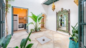 Une cour intérieure aménagée avec une cuisine, des plantes en pot, un miroir décoratif et un sol carrelé.