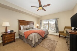 A bedroom with a bed, nightstand, desk, television, and a window with curtains. - NEW ski-in/ski-out 3 bedroom, private deck, views and plenty of bedding! (Granby)