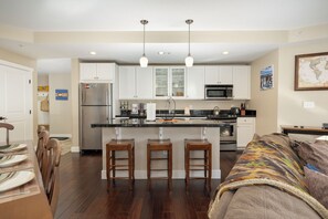 A modern kitchen with white cabinets, a stainless steel refrigerator, and a central island with bar stools. - NEW ski-in/ski-out 3 bedroom, private deck, views and plenty of bedding! (Granby)