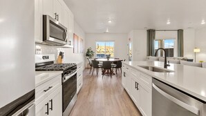Une cuisine moderne avec des meubles blancs, un îlot central et un coin repas avec des chaises.