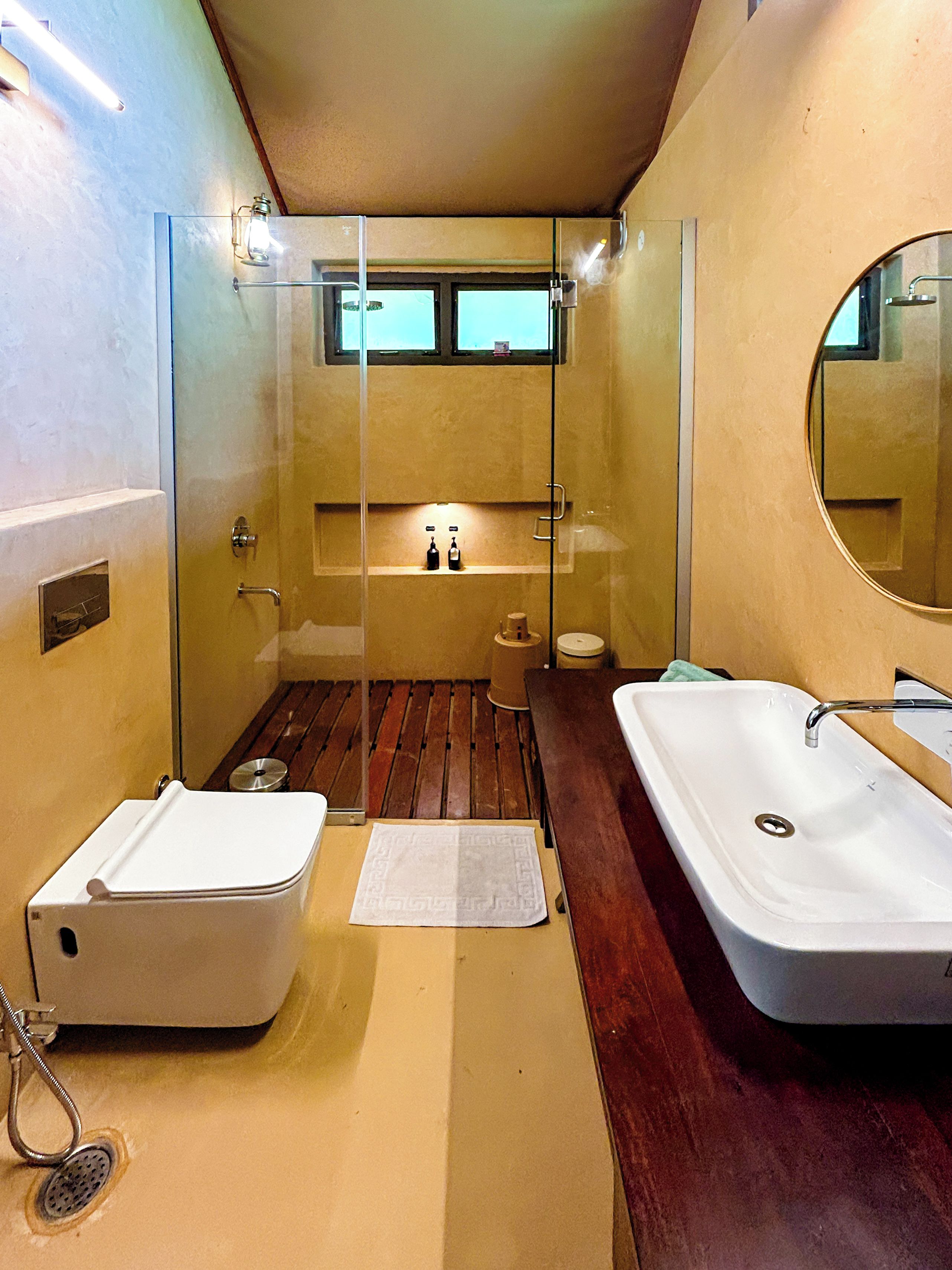 A compact bathroom with a glass-enclosed shower, a white sink, and a wooden vanity.