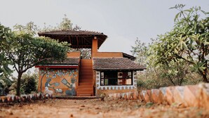 Un edificio tradicional con tejado de tejas, un mural y una escalera que conduce a una puerta.