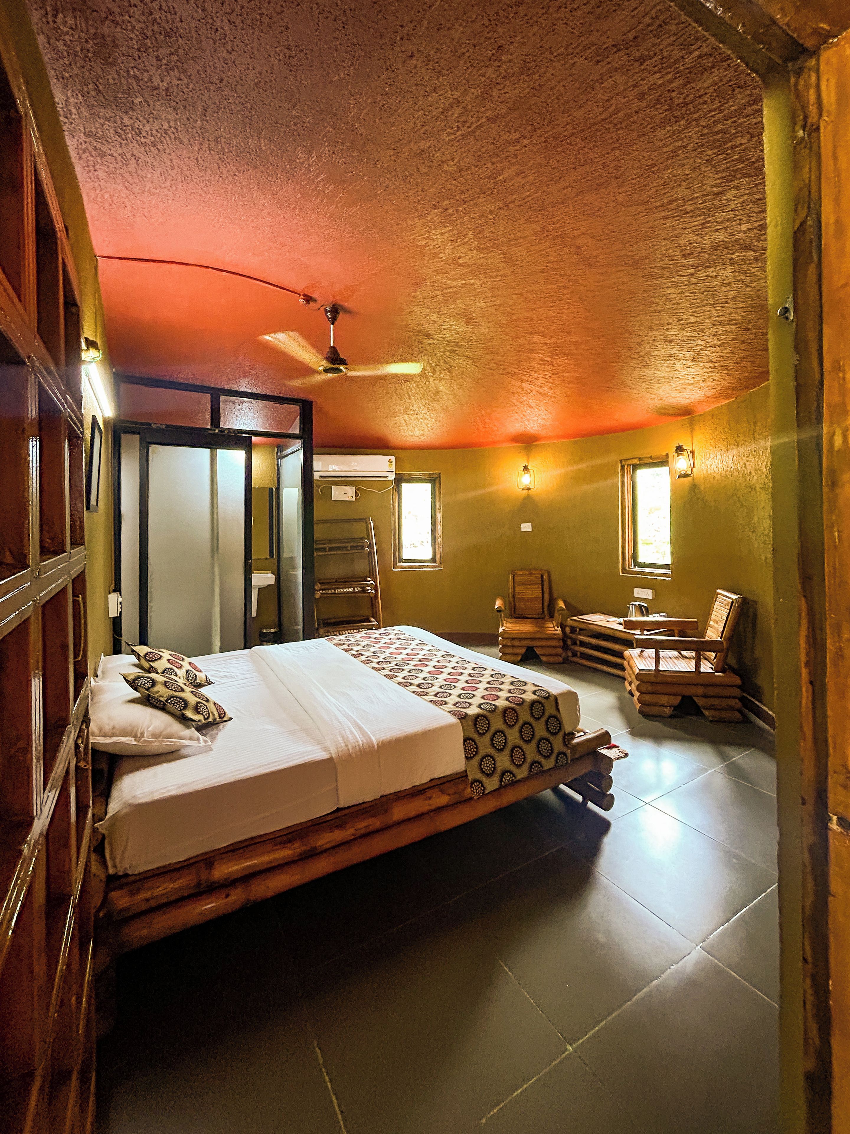 A room with a bed, a ceiling fan, a window, and a chair.