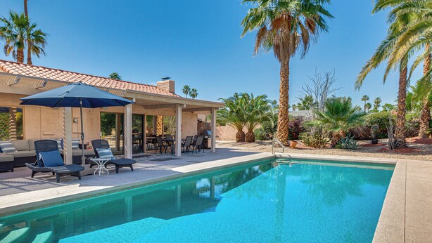 A swimming pool with lounge chairs and umbrellas, surrounded by palm trees and a covered patio area. - 1 Mi to Dtwn Palm Springs! Desert Escape w/ Pool (Palm Springs)