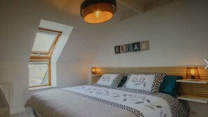 Un dormitorio con cama, un tragaluz, un cartel que dice 'RELAX' y una mesita de noche con lámpara.