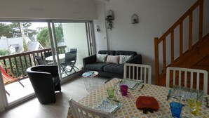 Una sala de estar moderna con sofá, mesa de comedor y sillas. Cuenta con un balcón con vistas al exterior.