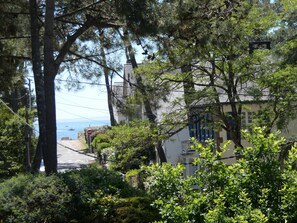 A coastal road with a 'no entry' sign, surrounded by dense greenery and buildings with visible chimneys. - Apartment 200m from the beach, XL comfort (beds 160 and 140) (Carnac)