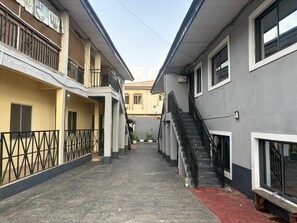 Un estrecho callejón entre edificios, con una escalera a la derecha y un balcón a la izquierda.