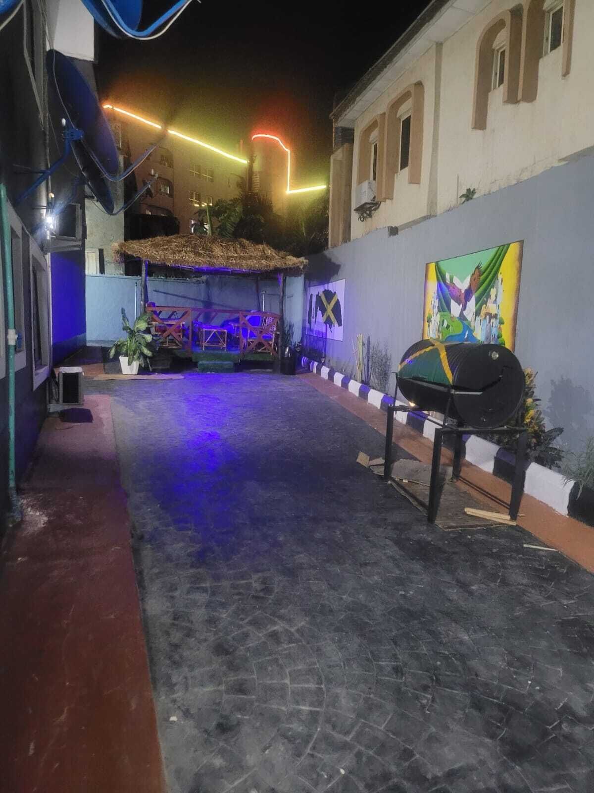 An outdoor patio area with a thatched roof, a stage, and colorful lighting.