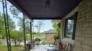 A covered porch with a table and chairs, a potted plant, and a view of the street.