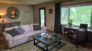 A living room with a sofa, coffee table, and a desk with a laptop.