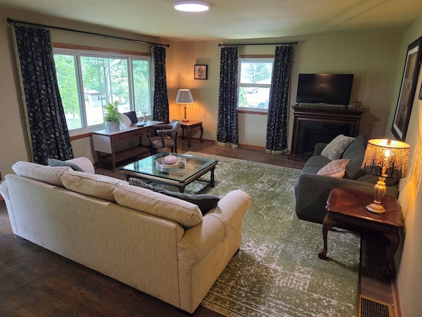 A living room with a sofa, a coffee table, a TV, and a fireplace.