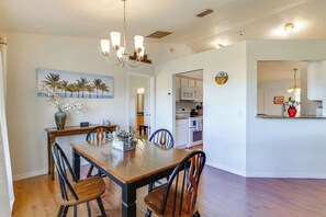 A dining area with a wooden table and chairs, a chandelier, and a kitchen in the background. - Work & Play in Apopka! Cozy Extended-stay Home (Apopka)