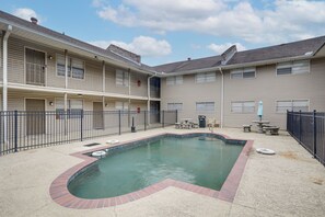 A multi-story building with a swimming pool, outdoor seating, and a fenced patio area.
