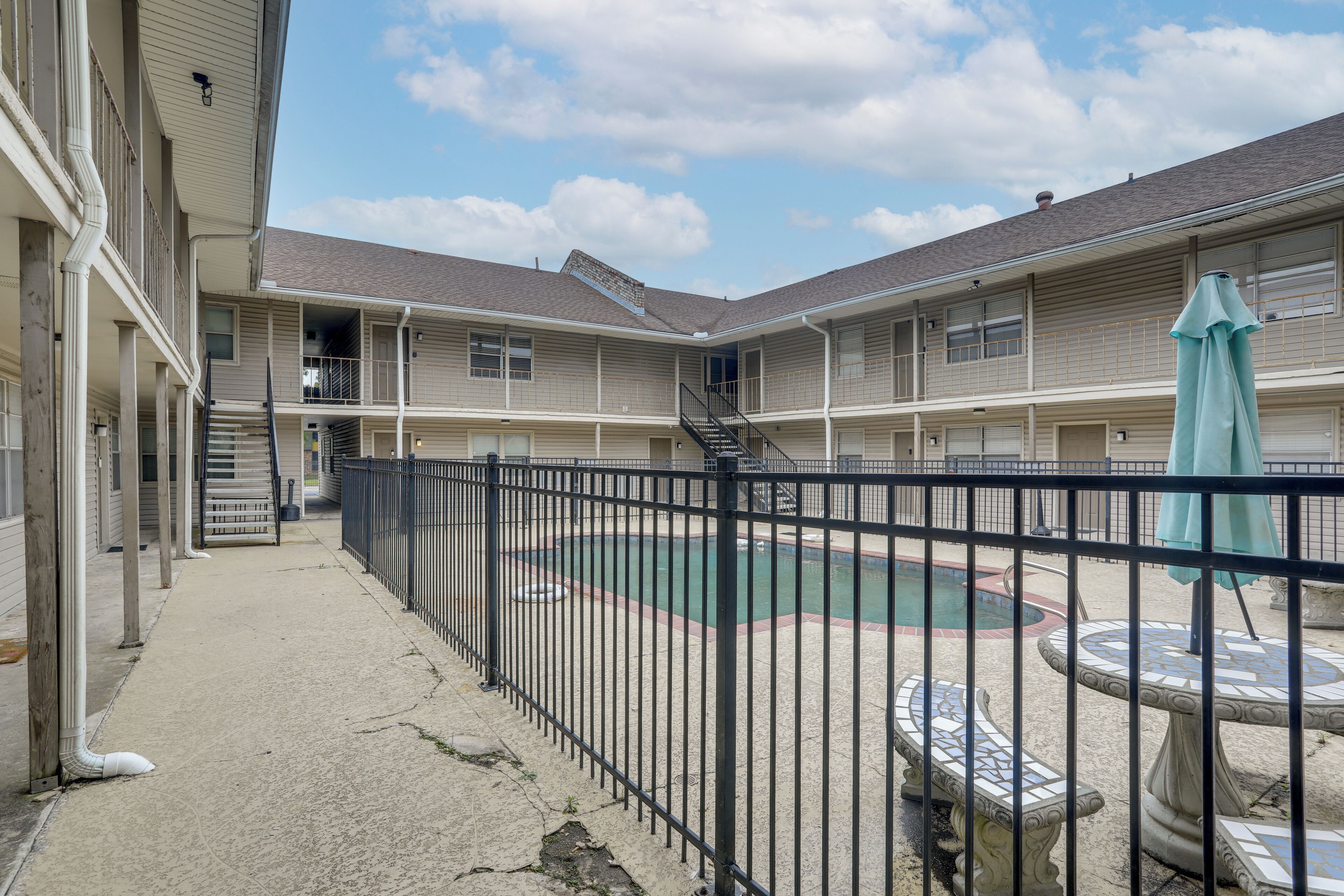 A courtyard with a swimming pool, a fenced area, and a building with multiple balconies.