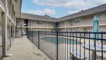 A courtyard with a swimming pool, a fenced area, and a building with multiple balconies.
