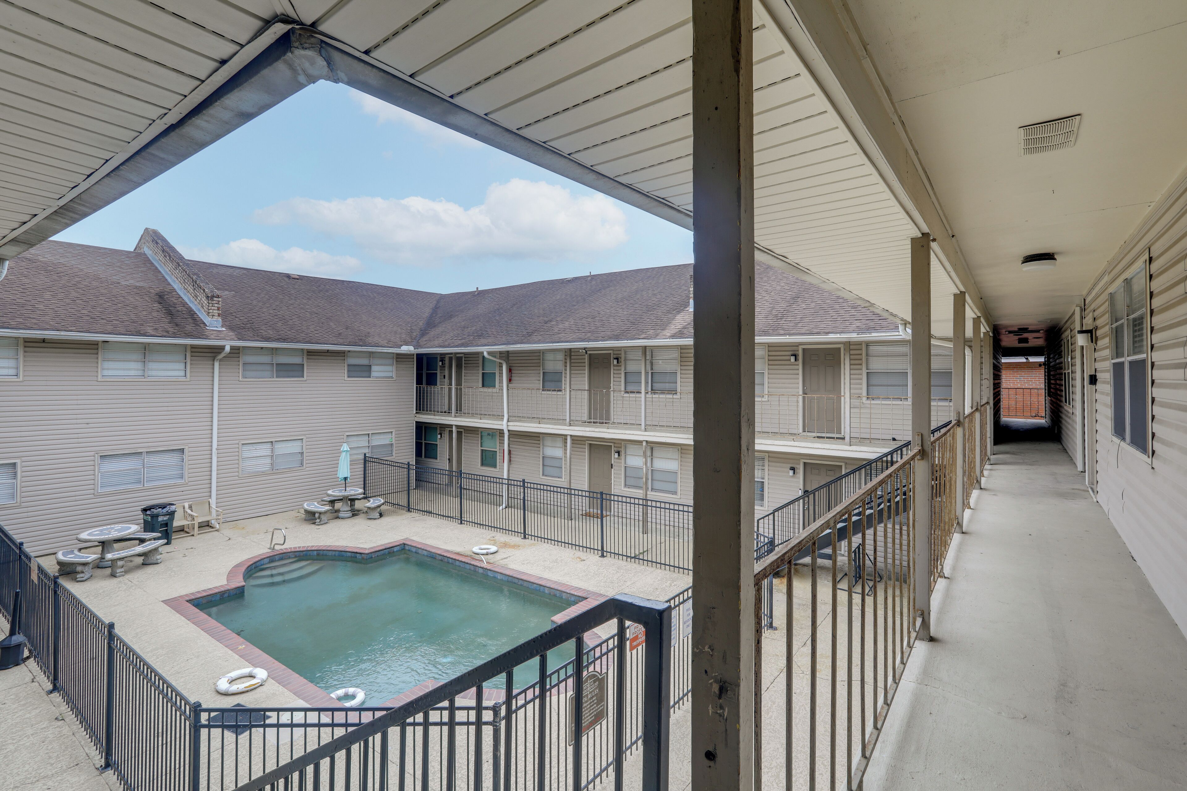 A multi-story building with a rooftop pool, outdoor seating, and a covered walkway.
